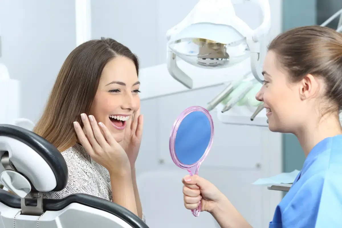 woman smiling in a mirror held by the dentist | La Belle Dental Clinic